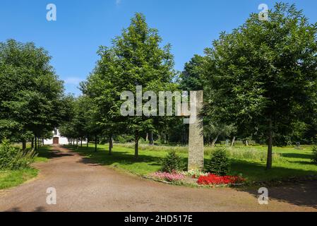 Marl, North Rhine-Westphalia, Germany - Memorial stone stone cross, behind European Peace House, former cemetery chapel in the Peace Park, the Old Cem Stock Photo