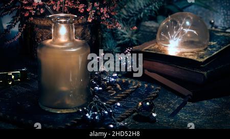 Magic lights with sparkles and orange glow in vintage glass jars. Lights and old books. Fir twigs and heather flowers. Romantic still life. Stock Photo