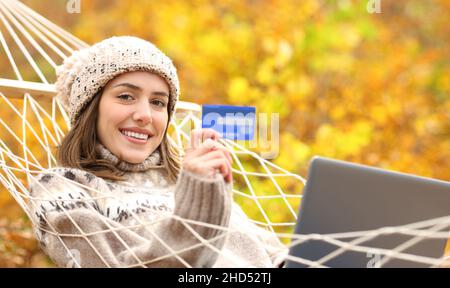 Happy woman on hammock showing credit card on winter holiday Stock Photo