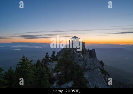 Silhouette of a person on a fire lookout at sunset Stock Photo