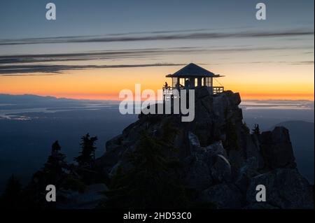 Silhouette of a woman on a fire lookout at sunset Stock Photo