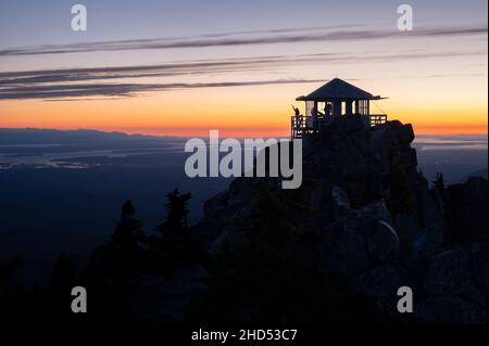 Silhouette of a person on a fire lookout at sunset Stock Photo