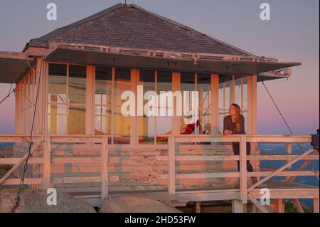 Female on the deck of Mount Pilchuck fire lookout at sunset Stock Photo