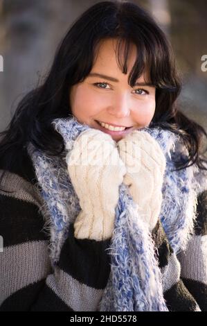 Beautiful young woman with soft sweater, scarf and mittens. Stock Photo