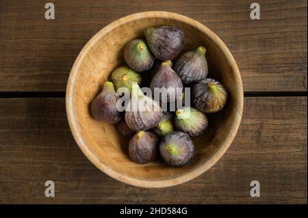 Top view figs in wooden bowl on wooden table, with copy space. High quality photo Stock Photo