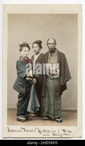 19th century vintage photograph - 1860's Japan carte de visite attributed to Felix Beato studio: Japanese yakonin, samurai officer, with wife and daughter. Stock Photo