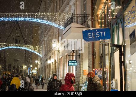 People walking in Tallinn historical center. 'Eesti' (Estonia) sign in focus. Shopping in heavy snow fall in Tallinn old town in winter. Stock Photo