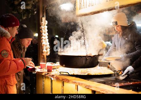 Tallinn, Estonia - Dec 5, 2021: Traditional Holiday food cooked and served at Christmas market on town hall square during winter evening. Fried cabbag Stock Photo