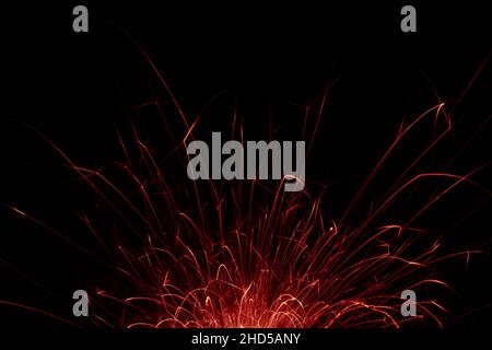 Fire embers particles over black background. Fire sparks background. Abstract dark glitter fire particles lights. bonfire in motion blur. Stock Photo