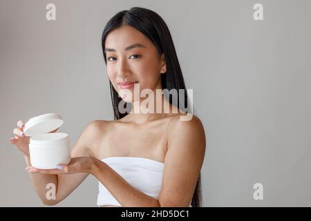 Asian young woman holding jar of cosmetic cream Stock Photo
