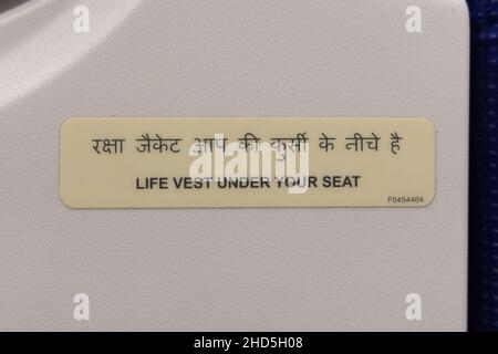 Airplane safety instruction sticker telling passengers that life vest is under the seat in case of emergency landing Stock Photo