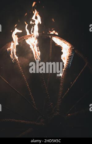 fire flames on an old cart wheel made of iron and spokes wrapped in rope Stock Photo