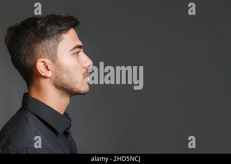 Close-up profile view portrait of young handsome serious guy  Stock Photo