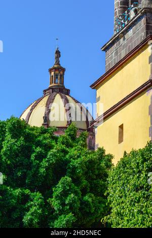 The dome rises above the treetops along with the bell-tower of the Convent of the Immaculate Conception church in San Miguel de Allende, Mexico Stock Photo