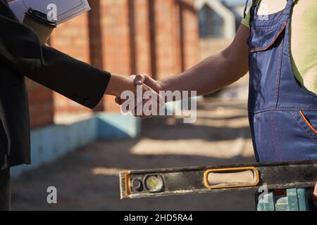 Civil engineer and worker shaking hands on site Stock Photo