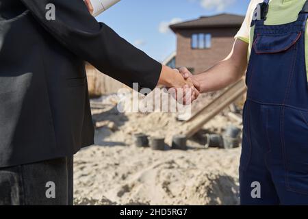 Two people shaking hands on construction area Stock Photo