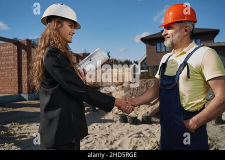 Female civil engineer and builder shaking hands on site Stock Photo