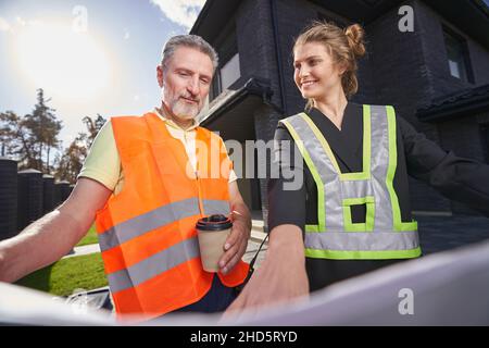 Satisfied construction engineer pointing out something on drawings to worker Stock Photo