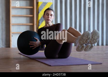 Woman doing russian twists with a medicine ball. Stock Photo