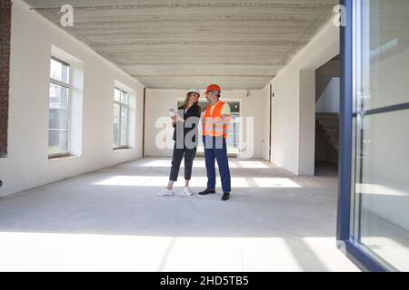 Woman engineer talking with construction worker inside house Stock Photo