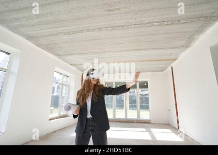 Joyful woman designer using VR glasses and reaching out hand Stock Photo