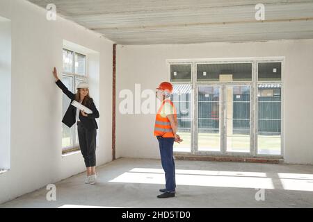 Woman explaining builder his work about the wall Stock Photo
