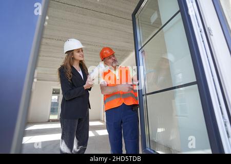 Young woman designer examining door with housebuilder Stock Photo