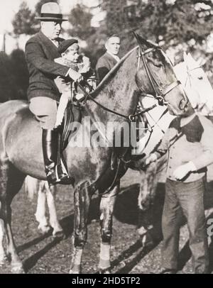 Vintage early 20th century press photograph: Italian dictator, Benito Mussolini, on horse with son, Villa Torlonia, Italy. Stock Photo