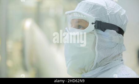 Worker in apron, cap, gloves with tablet checking process at production line in factory. Quality Control Workers Examining Pills in Lab. Pharmaceutica Stock Photo