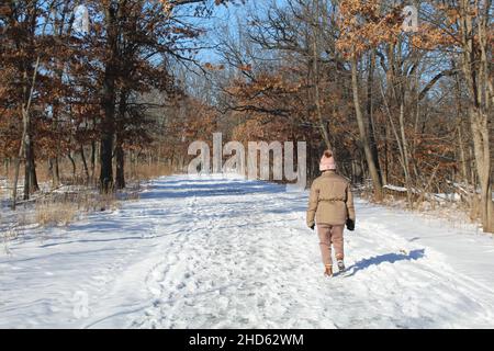 Woman walking on the North Branch Trail in winter at Miami Woods with two people far away Stock Photo