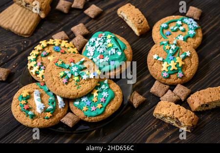 Tasty homemade cookies on wooden table, pile of various biscuit decorated sugar glaze. Assorted dessert food, festive delicious eating. Different oatm Stock Photo