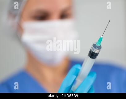 Experienced masked nurse prepared a syringe for injection, filling it with medicine Stock Photo