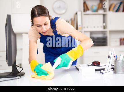 Portrait of a young woman cleaning an office desk Stock Photo