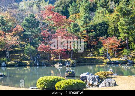 An autumn garden at the Tenryu-Ji Temple in Kyoto Japan with the colors of fall reflecting in the calm water of the pond. Stock Photo