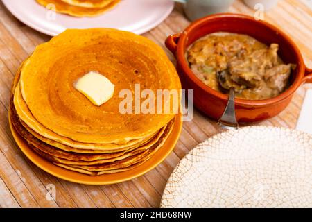 Thin pancakes with butter and machanka of meat with vegetables and mushrooms Stock Photo