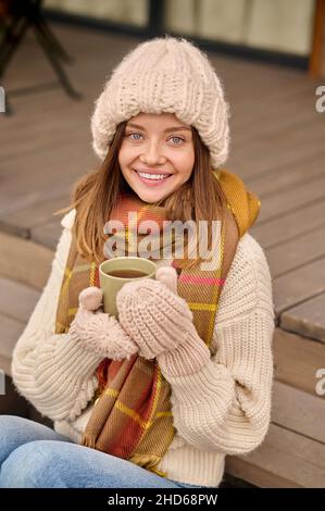 Woman with coffee sitting on veranda looking at camera Stock Photo