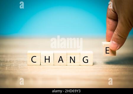 Hand holding a wooden block letter e, put on the meaning of the word change, business idea, change in new things, adjusting plans to succeed. Stock Photo