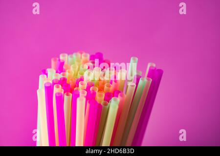Colorful plastic straws against pink background Stock Photo