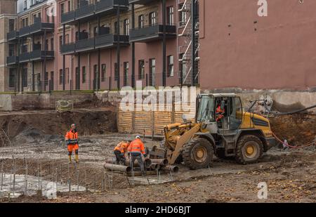 Construction workers loading old pipes on a large construction site Stock Photo
