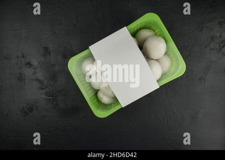 farm mushrooms champignons in plastic packaging on a black background. top view. logo layout design Stock Photo
