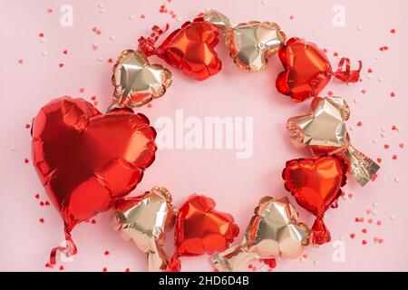 One big red and many small Air Balloons of heart shaped foil on festive pink background. Love concept. Holiday celebration. Valentine's Day or wedding Stock Photo