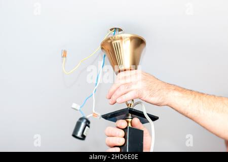 electrician hands arranging a lamp on the ceiling, indoor close up Stock Photo