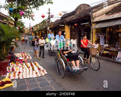 Hoi An, Vietnam - March 13, 2016: Cycle rickshaws taking tourists through Hoi An old town in the evening Stock Photo