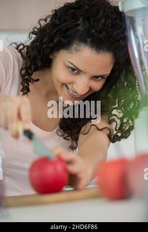woman cooking and cutting apple on wooden cutting board Stock Photo