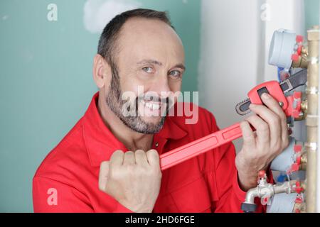male plumber fixing water meter with adjustable wrench Stock Photo