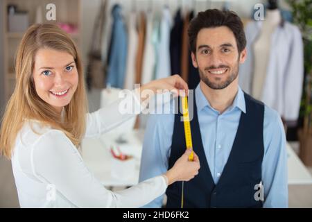 young needlewoman taking measures of male client Stock Photo