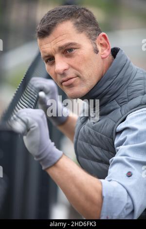 worker installing welded metal mesh fence Stock Photo