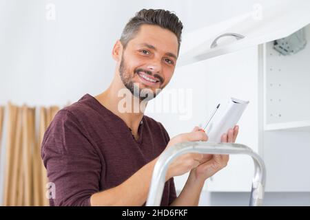 serviceman in overall working on cupboard Stock Photo