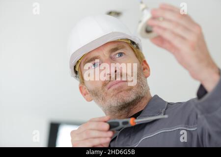 mid-adult man fixing light bulb wiring in new house Stock Photo