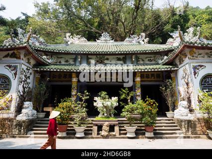Da Nang, Vietnam - March 13, 2016: Vietnamese woman in conical hat walking inside the Buddhist temple on the top of Thuy Son mountain, the most import Stock Photo